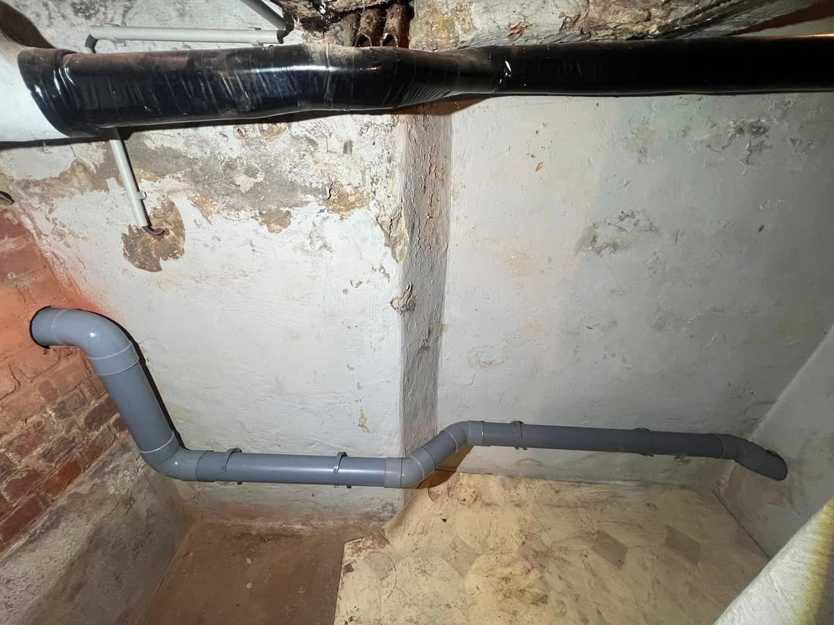Canalisations PVC le long d'un mur de cave — égoutage et raccordements