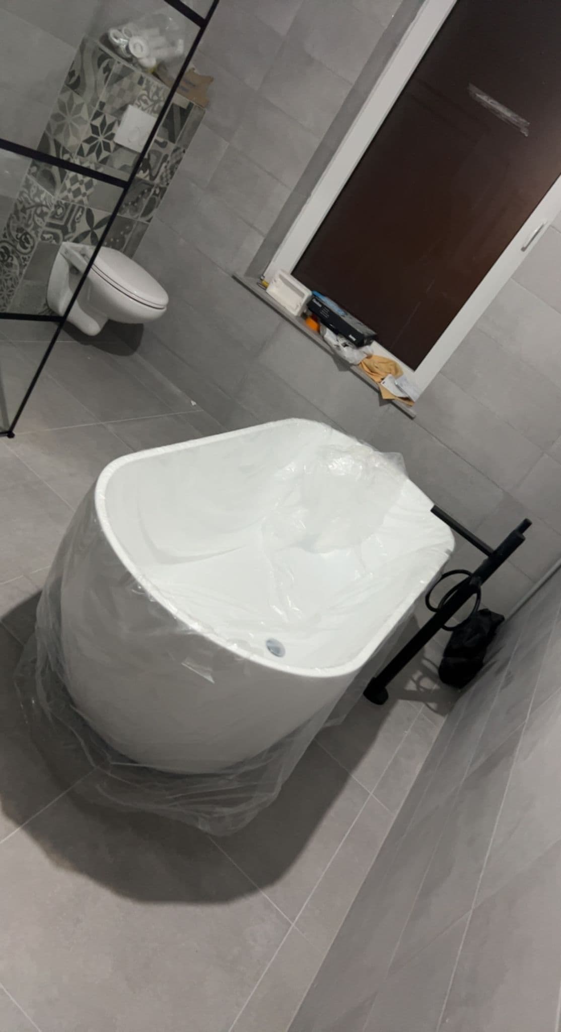 Installation sanitaire avec baignoire îlot, robinetterie noire et finitions soignées